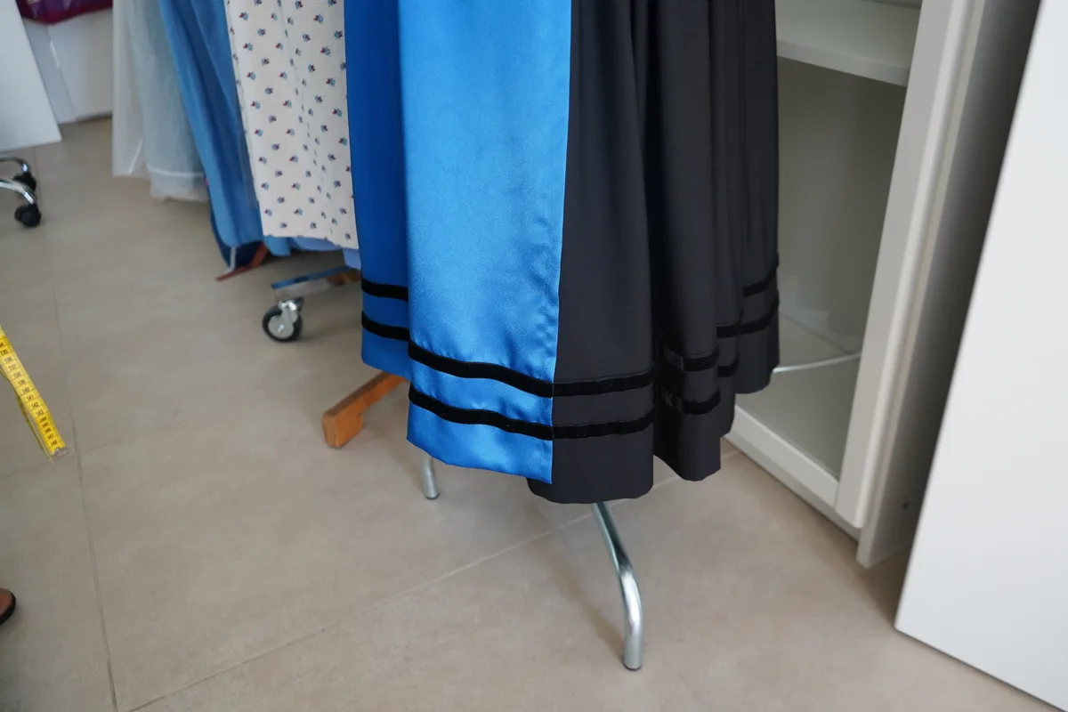 Der Saum einer Tracht ist mit einem Band verziert.